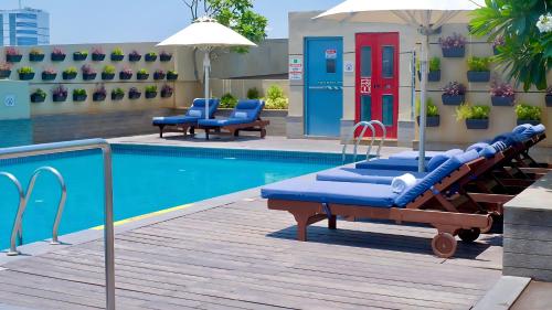 a swimming pool with two chaise lounges next to a building at Holiday Inn Chennai OMR IT Expressway, an IHG Hotel in Chennai