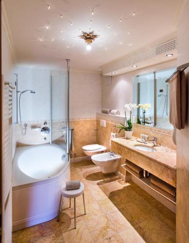 a bathroom with a tub and a toilet and a sink at Alpen Hotel Corona in Vigo di Fassa