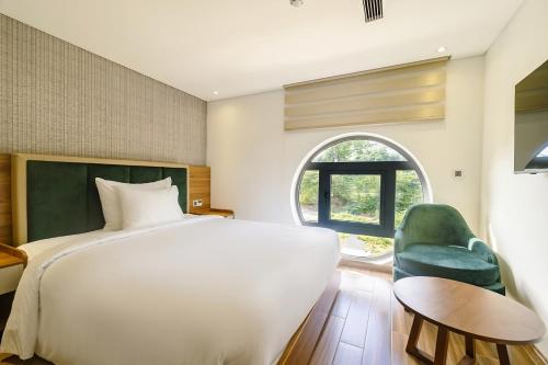 um quarto com uma cama branca e uma cadeira verde em The Tahiti Beach Hotel em Phu Quoc