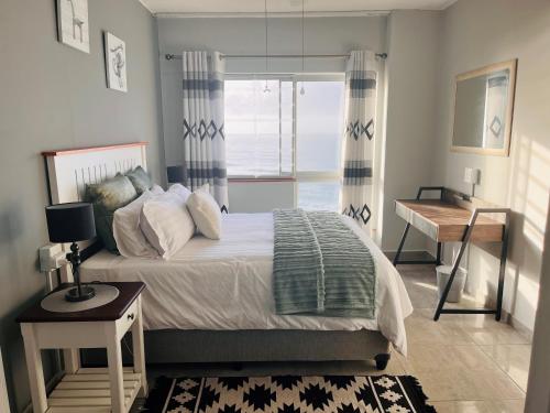 a bedroom with a bed and a desk and a window at Santana 804 Beachfront Apartment with spectacular sea views in Margate