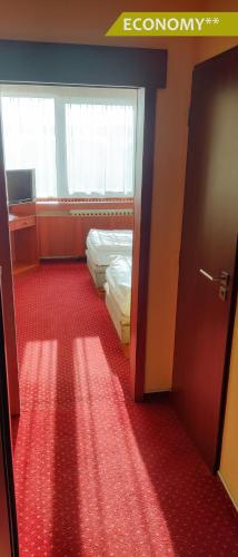 a room with two beds and a red carpet at Hotel Ludmila in Mělník