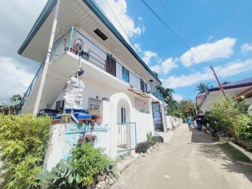 a white building with a balcony on a street at Gaja Go Dive & Inn in Moalboal