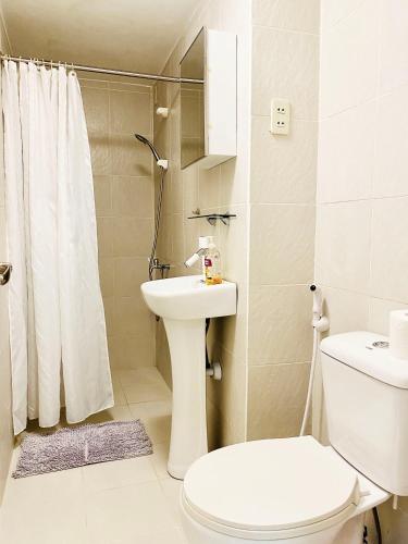 a white bathroom with a toilet and a sink at Little Norway Guesthouse - Mactan Cebu International Airport in Mactan