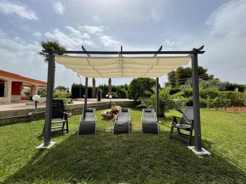 een tuinhuisje met stoelen eronder in een tuin bij Country House in San Vito dei Normanni