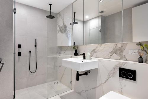 y baño blanco con lavabo y ducha. en The Horizon Apartments by Urban Rest en Sídney