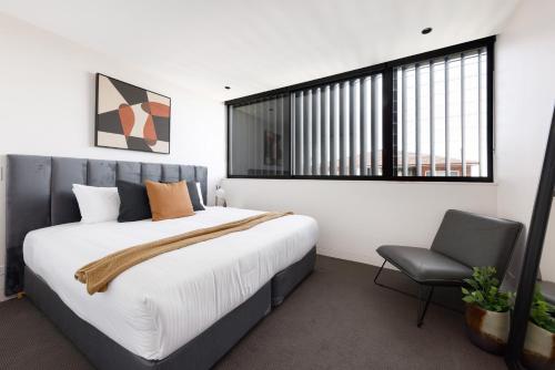 a bedroom with a large bed and a chair at The Horizon Apartments by Urban Rest in Sydney