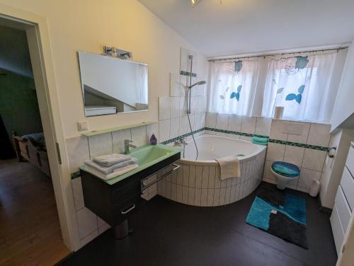 ein Badezimmer mit einer Badewanne, einem Waschbecken und einem WC in der Unterkunft Haus Edelweiss Jungholz in Jungholz
