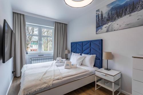 Apart-Invest Apartament Latte في شكلارسكا بوريبا: غرفة نوم مع سرير كبير مع اللوح الأمامي الأزرق