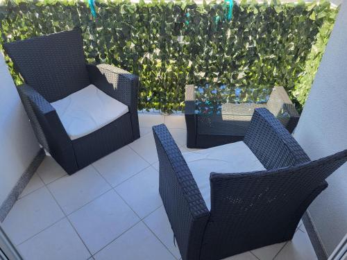 - un balcon avec 2 chaises, une table et une haie dans l'établissement Apartman Roko, à Slatine
