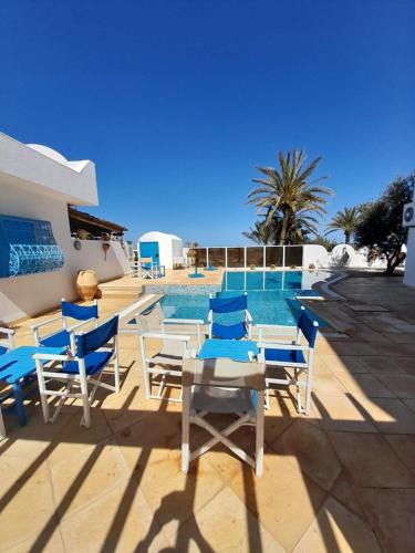 a pool with blue and white chairs and a table at Dar Lagune Djerba in Al Ḩaddādah