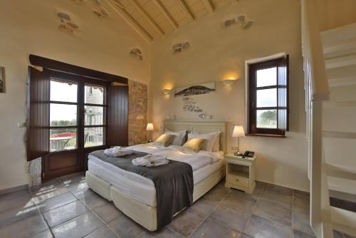 a bedroom with a large bed and two windows at Castello Antico Hotel in Gythio