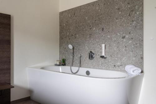 a white bath tub in a bathroom with a stone wall at Freiraum 9 Living Apartment in Sankt Johann im Pongau