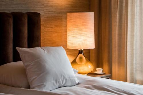 a bed with a white pillow and a lamp at Billingehus in Skövde