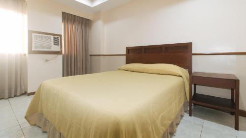 um quarto com uma cama grande e uma mesa de cabeceira e uma cama sidx sidx sidx em Garden Plaza Hotel Manila em Manila