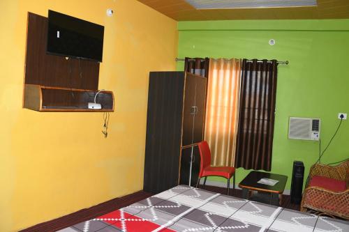 Habitación con TV y silla en Hotel Mountain View And Rooftop Restaurant, en Pithorāgarh