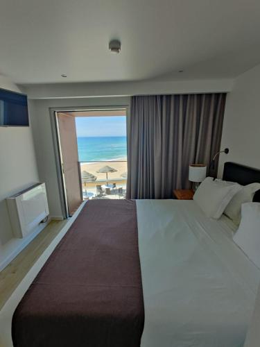a bedroom with a large bed and a view of the beach at Promar - Eco Beach & Spa Hotel in Maceira