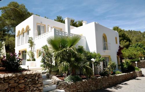 uma casa branca com uma palmeira em frente em Hacienda Encanto del Rio em Es Figueral Beach