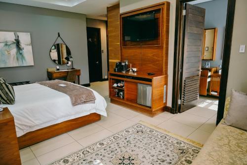 a bedroom with a bed and a flat screen tv at Tredenham Boutique Hotel in Bloemfontein
