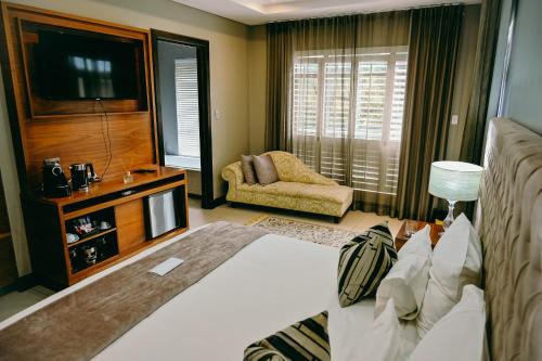 a bedroom with a bed and a television and a chair at Tredenham Boutique Hotel in Bloemfontein
