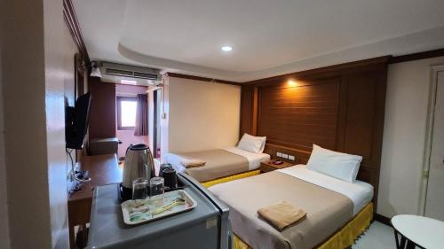 a small hotel room with two beds and a desk at White Rose​ Hotel​ II​ in Nong Prue