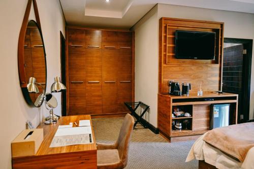 a bedroom with a bed and a desk and a television at Tredenham Boutique Hotel in Bloemfontein