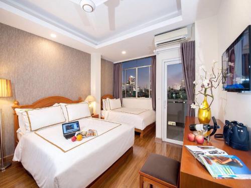 Habitación de hotel con 2 camas, escritorio y TV. en Lan Anh Hotel en Ho Chi Minh