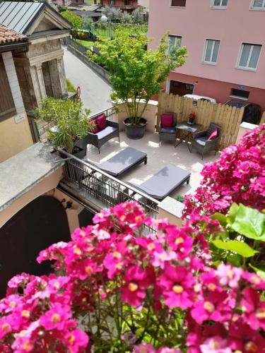 a balcony with tables and chairs and pink flowers at Maison Annabelle in Ceniga