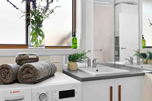 a white kitchen with two sinks and a washing machine at Terra Mare in Geelong West