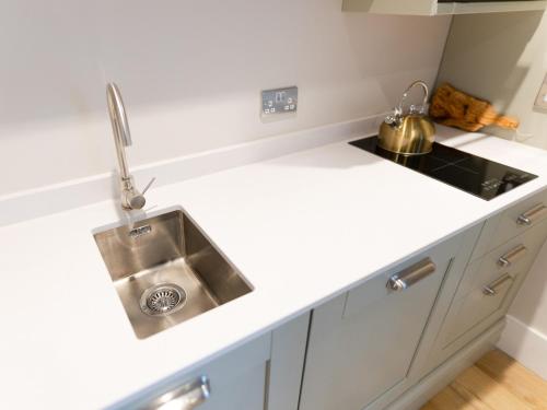 a white kitchen with a sink and a counter at Skye Studio - Ukc6566 in Mallaig