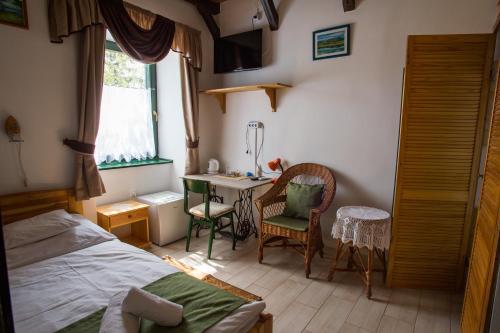 a bedroom with a bed and a desk and a window at Piros Ponty Panzió in Poroszló
