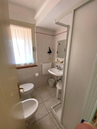 a bathroom with two toilets and a sink at Hotel Due Torri in Porto Azzurro