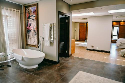 a bathroom with a large white bath tub in a room at Tredenham Boutique Hotel in Bloemfontein
