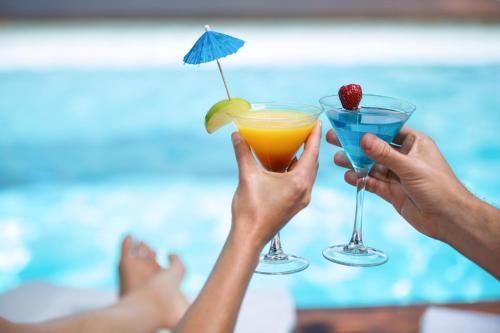 two people holding up cocktails at a pool at Hôtel Le Refuge des Sources in Digne-les-Bains