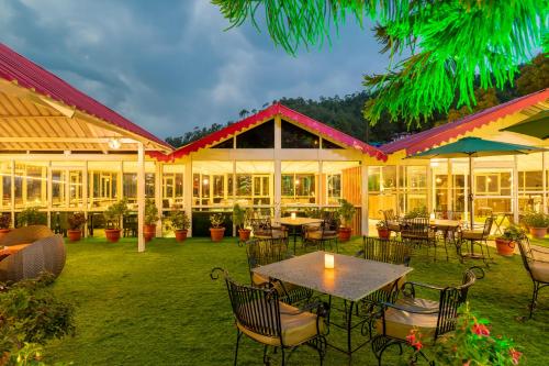 a patio with tables and chairs in front of a building at Maple Resort Chail in Shimla