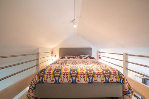 a bedroom with a bed with a colorful comforter at L'Escale de Jules et Lily in Bligny-lès-Beaune
