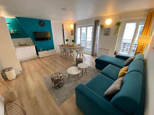 uma sala de estar com um sofá azul e uma mesa em Le Cocon de Jeanne em Rouen