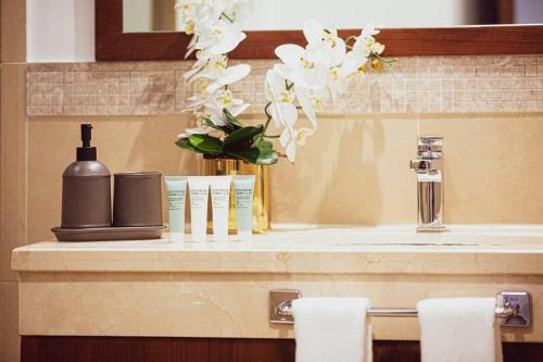 a bathroom counter with a sink with a vase of flowers at Magnificent New 3 BR with Stunning View to Burj Khalifa & Fountain view in Dubai