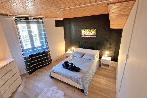 een slaapkamer met een bed met twee schoenen erop bij La Maison De Nelly labellisé 3* in Mouzon