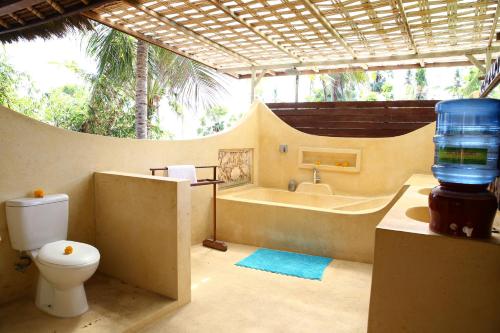 a bathroom with a toilet and a bath tub at Seraya Shores Bali in Seraya