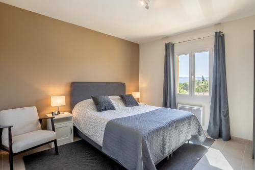 a bedroom with a bed and a chair and a window at Domitia Roussillon Appartement Luberon in Roussillon