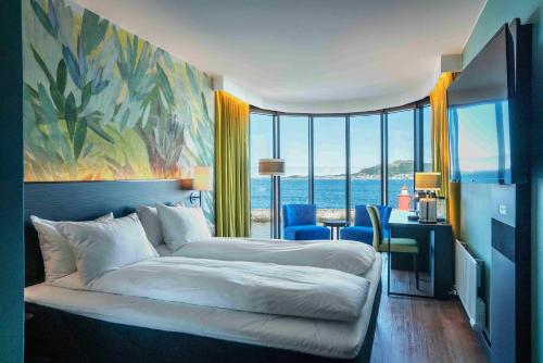 a bedroom with a bed and a desk and a large window at Thon Hotel Ålesund in Ålesund