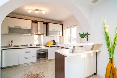 a kitchen with white cabinets and a large window at Apartments Sandito in Mlini