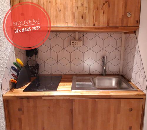 a kitchen counter with a sink and a sign on the wall at L'Annexe in Môtiers