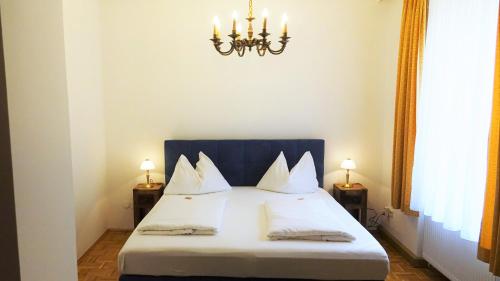 a bedroom with a bed with white pillows and a chandelier at Hotel Kindler 2,0 Self-Check-In in Leoben