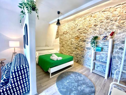 ein Schlafzimmer mit einem grünen Bett und einer Steinmauer in der Unterkunft Casa Vacanze Controvento in Taormina