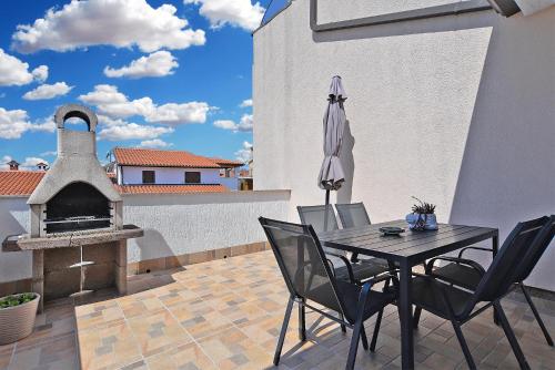 un patio con mesa, sombrilla y chimenea en Apartments Milka 2074, en Poreč