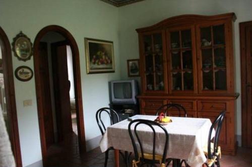a dining room with a table with chairs and a tv at Villino Oliva in Pomonte