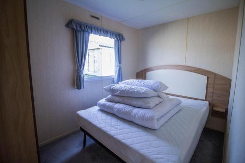 uma pilha de toalhas brancas sentadas em cima de uma cama em Lovely Caravan With Decking At Manor Park Nearby Hunstanton Beach Ref 23017t em Hunstanton