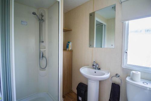 ein Bad mit einem Waschbecken, einer Dusche und einem Spiegel in der Unterkunft Lovely Caravan With Decking At Manor Park Nearby Hunstanton Beach Ref 23017t in Hunstanton