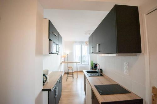 une cuisine avec des armoires noires et un comptoir en bois dans l'établissement Superbe appartement 2 pièces avec vue mer - Brest, à Brest